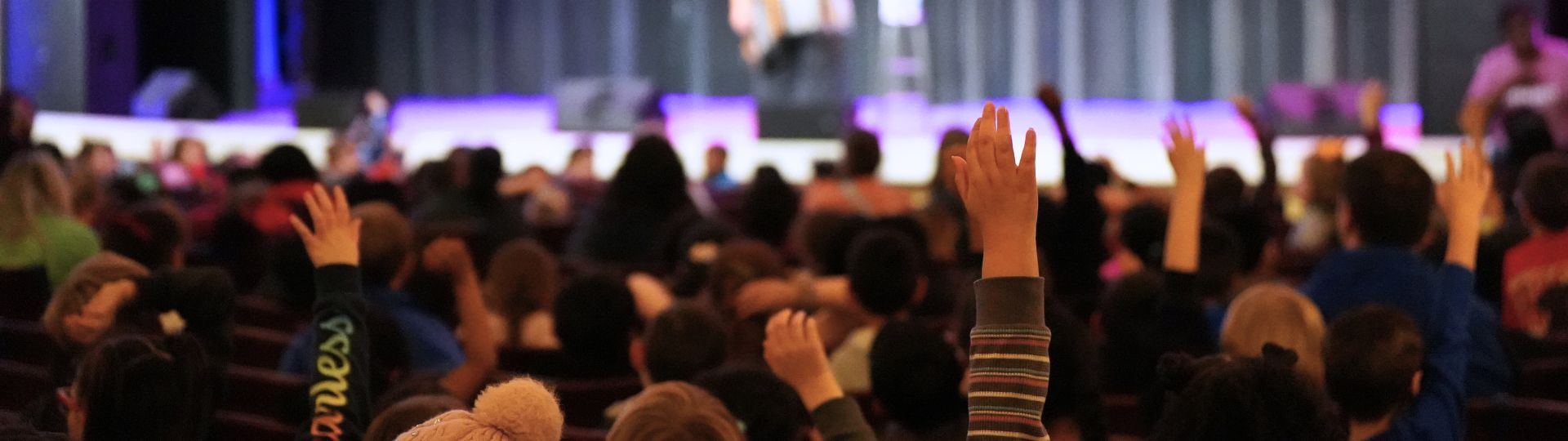 Student audience raises hands during performance
